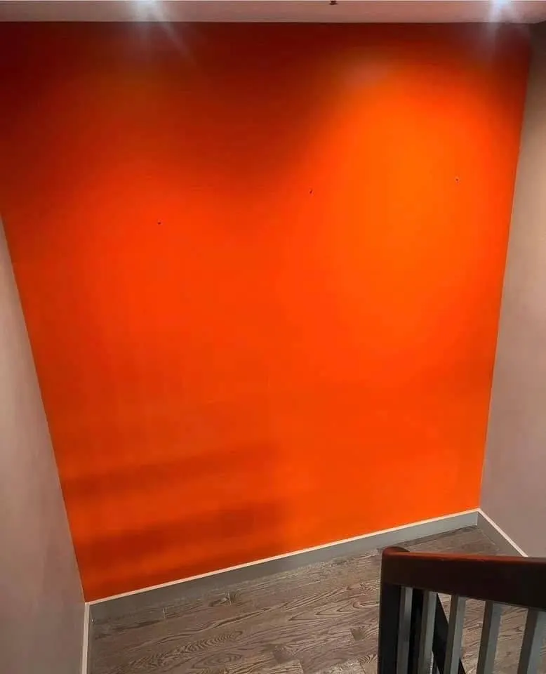 Burnt-orange accent wall with clean cut lines against a light ceiling and baseboard