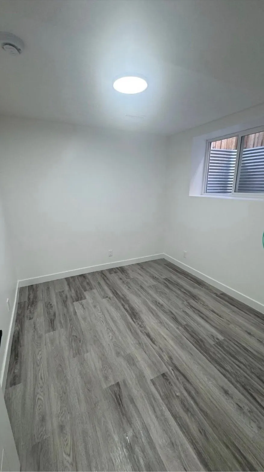 Basement bedroom with vinyl plank flooring, a window and recessed lighting