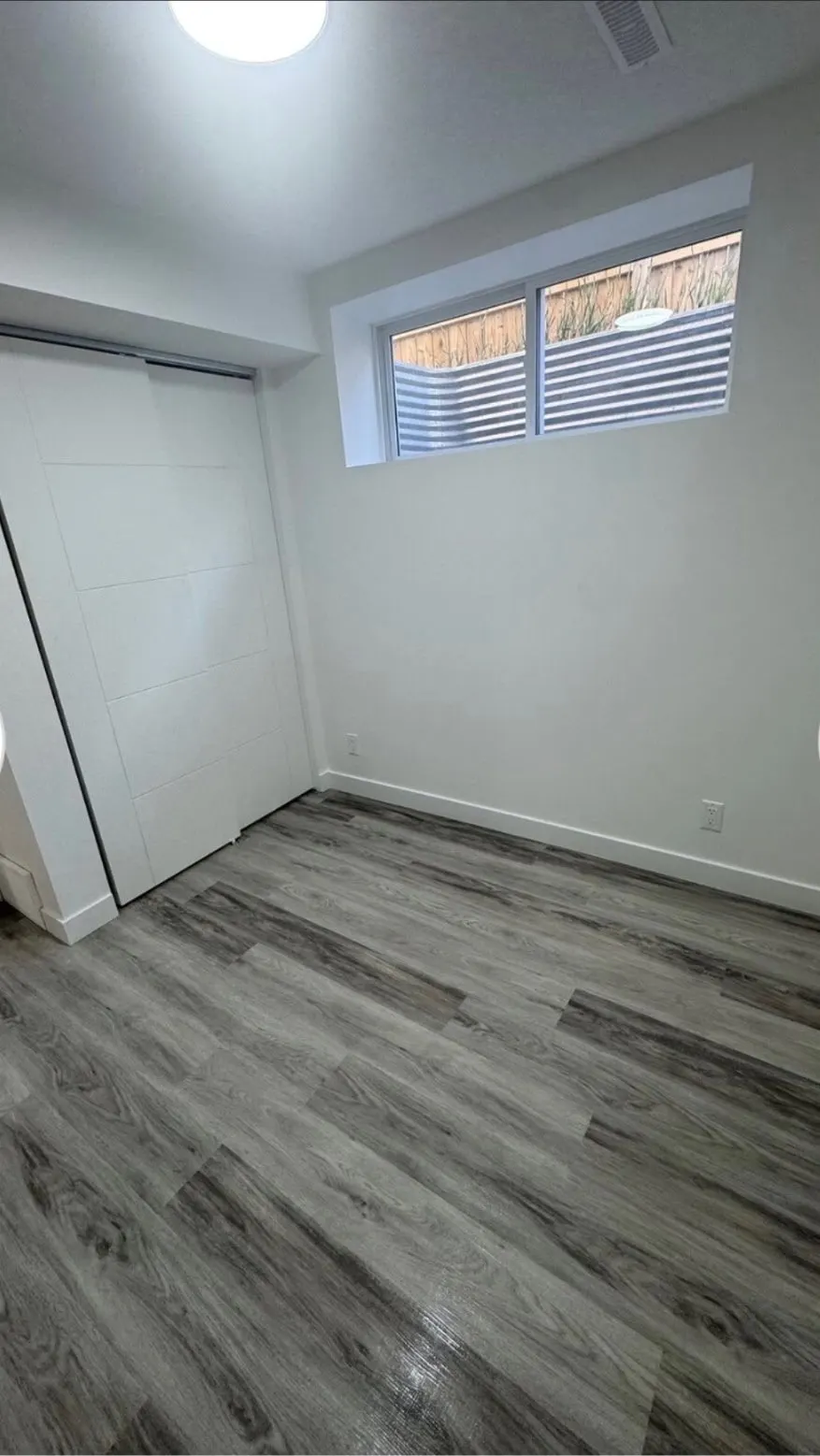 Basement suite bedroom with an egress window and vinyl plank flooring