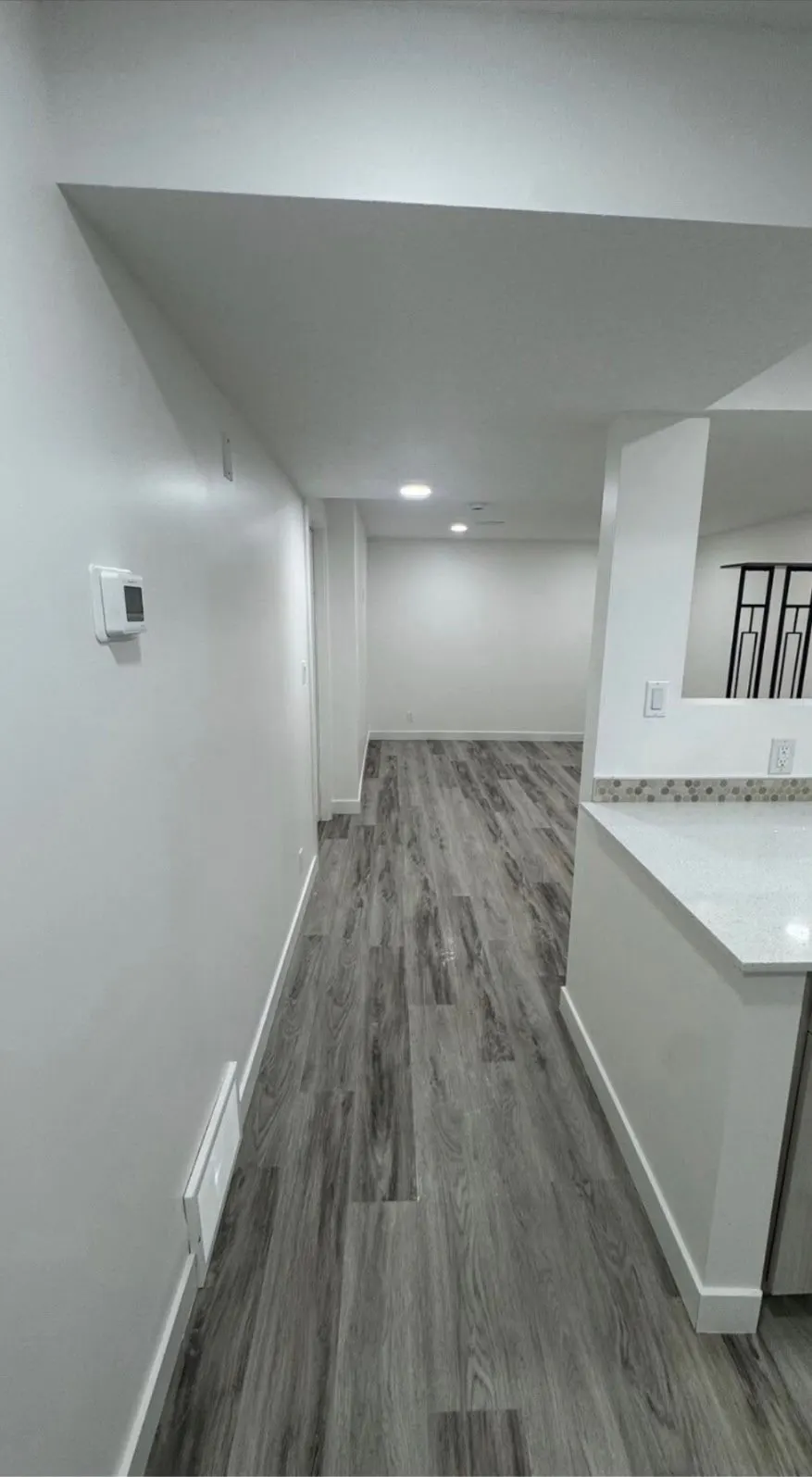 Basement suite hallway with vinyl plank flooring and a separate thermostat on the wall