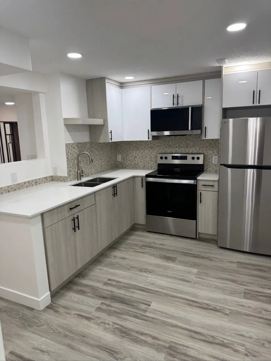 Basement secondary suite kitchen with white upper cabinets, grey lowers, quartz counters and stainless appliances