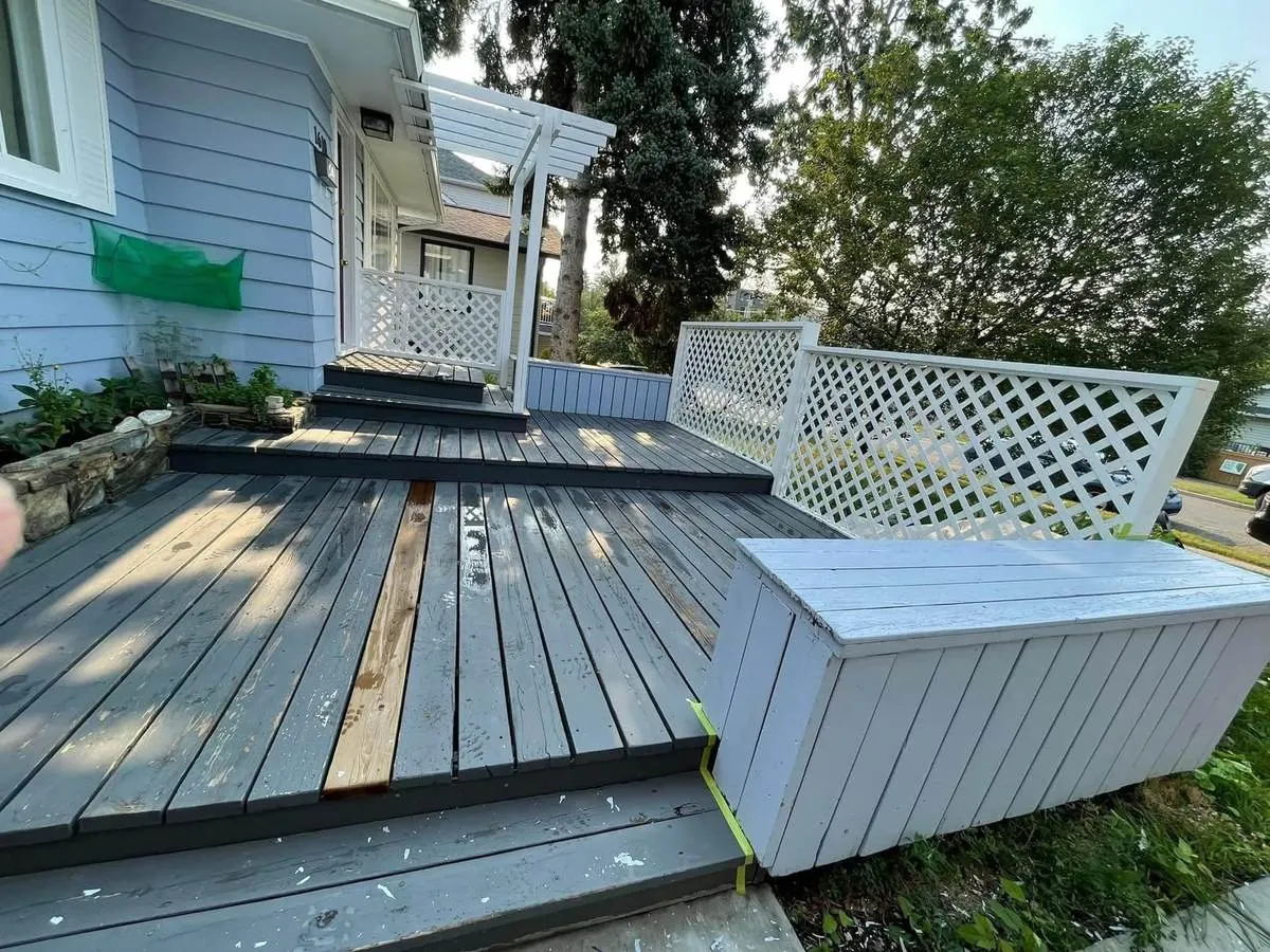 Front deck mid-refinish with bare replacement boards and worn grey stain
