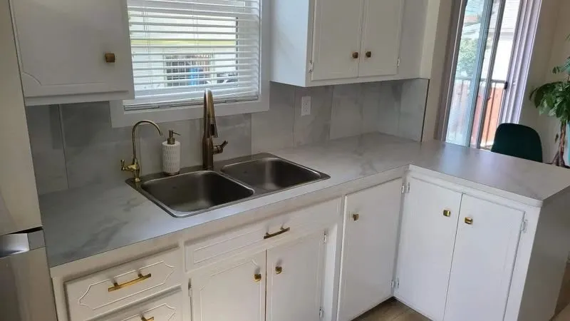 Kitchen with white painted cabinets, brushed gold hardware and a gold faucet